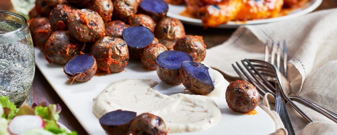 A plate of brilliantly purple little potatoes with crema.