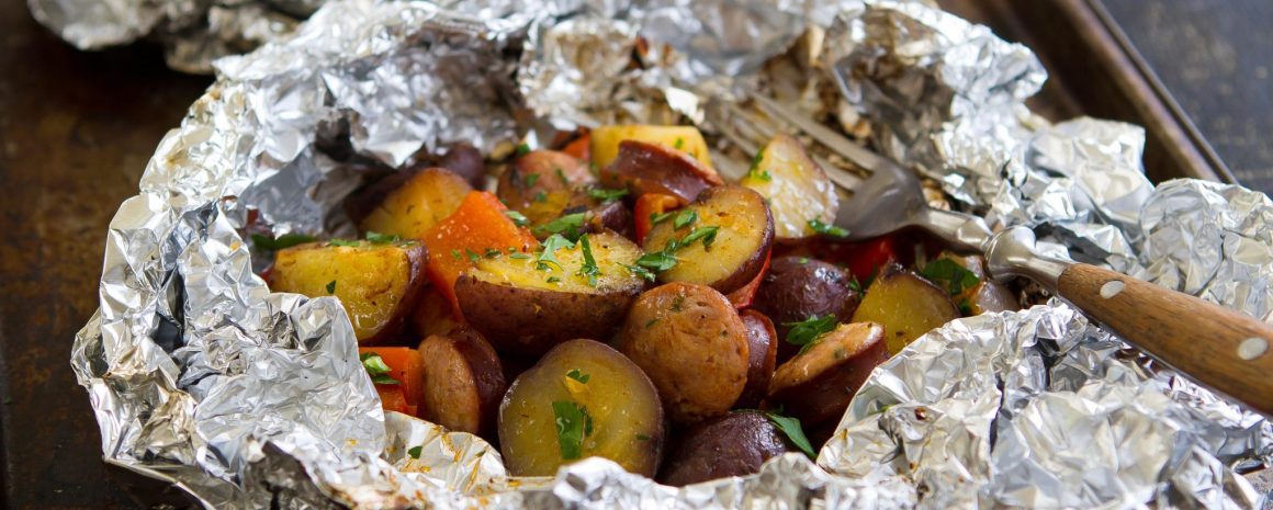 A foil packet with grilled sausage and potatoes.