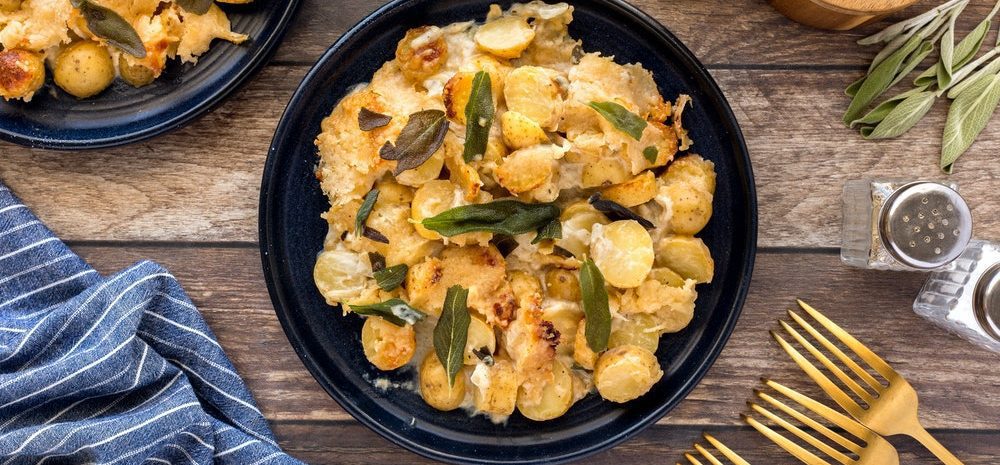 Layers of creamy, cheesy, little potatoes in a bowl topped with sage.