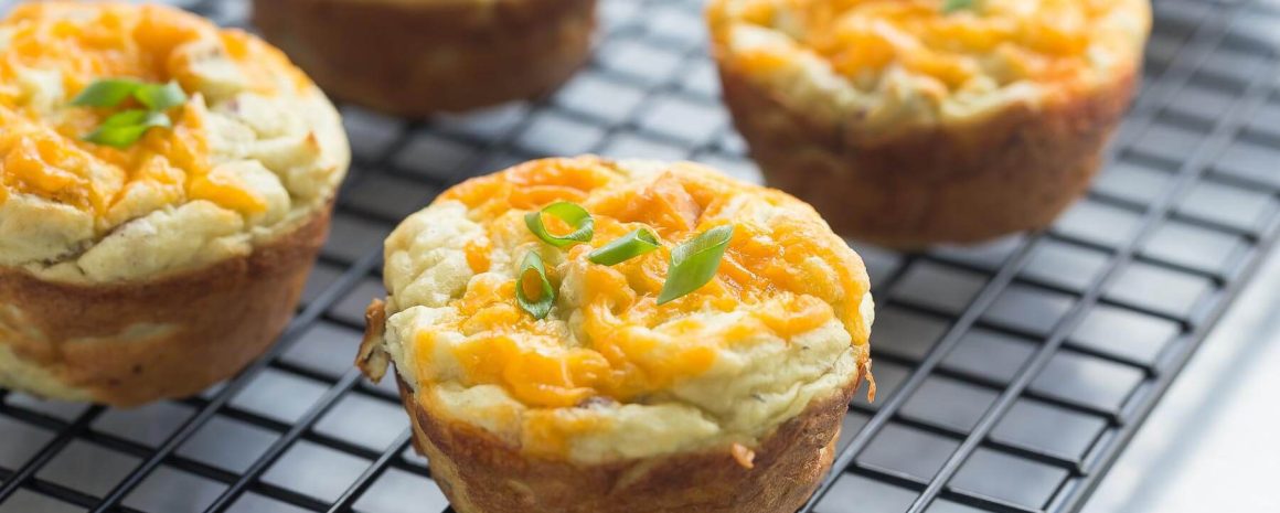 A cooling rack with cheese stuffed mashed potato puffs on it.