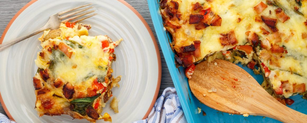 A baking dish with a plate next to it. Both have very delicious looking breakfast casserole on them.