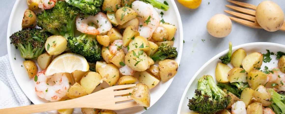 Sheet pan shrimp and potatoes in little plates with cute wooden forks.