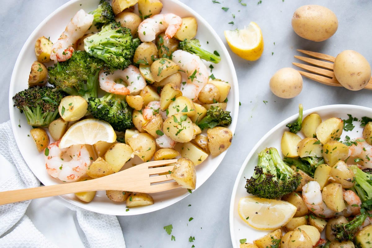 Sheet pan shrimp and potatoes in little plates with cute wooden forks.