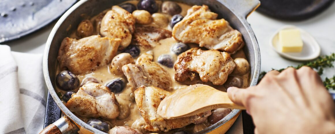 A pan with chicken and potatoes in it.